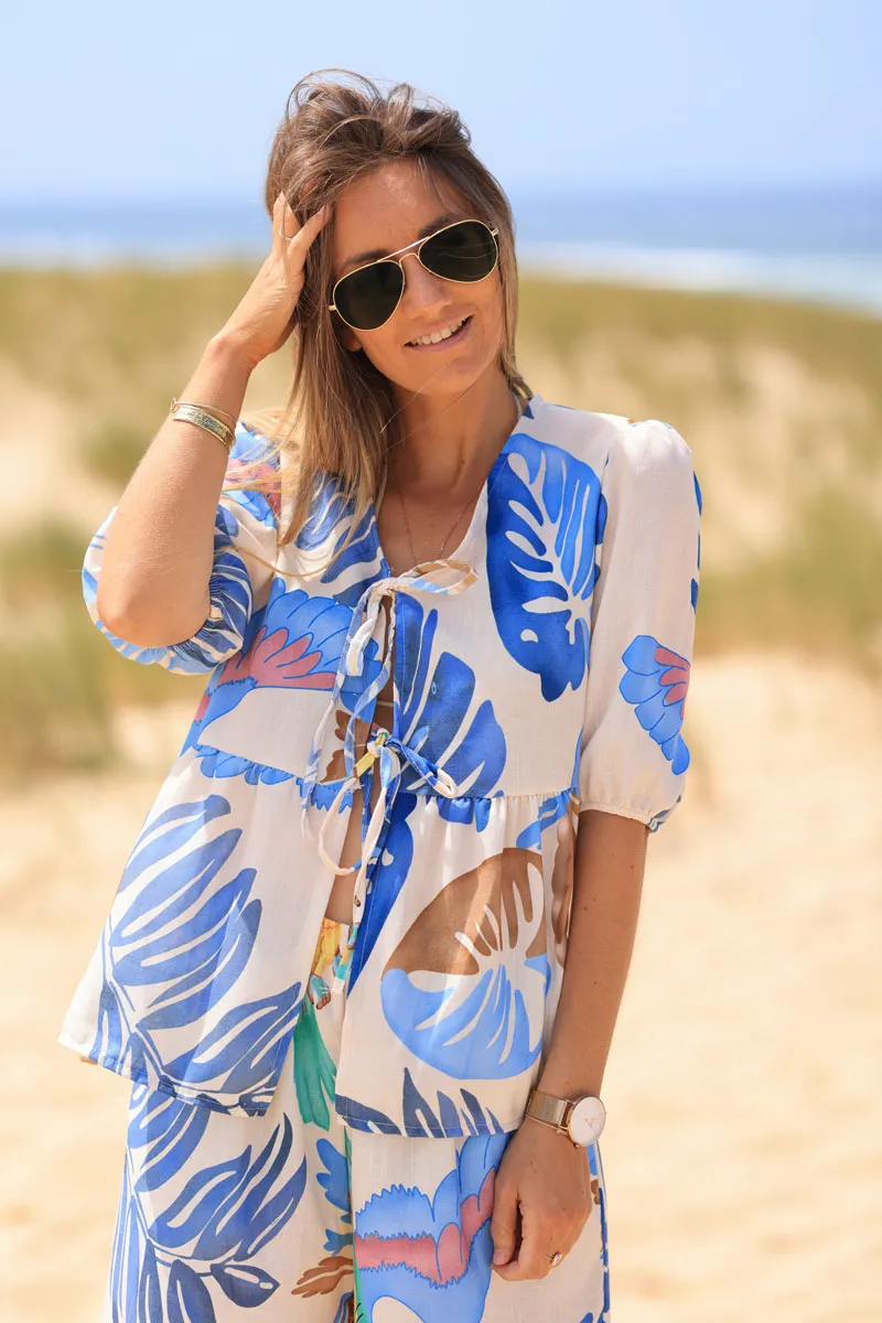 Cream tie-up top with blue watercolor palm leaves and parrots print.
